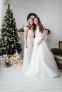 Beautiful bride in luxury wedding dress and pretty bridesmaid in dresse in decorated christmas studio. weddind in Christmas