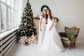 Beautiful bride in luxury wedding dress and pretty bridesmaid in dresse in decorated christmas studio. weddind in Christmas