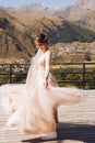 Beautiful bride in a nice dress stands on the terasse with great mountain view in Georgia Royalty Free Stock Photo