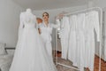 a beautiful bride poses in a white robe next to her wedding dress and her friends' dresses