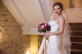 Beautiful bride posing with a bouquet of flowers smiling and standing on the stairs.The Obligatory wedding dress Royalty Free Stock Photo