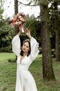 Beautiful bride posing in a wedding white dress holding a bridal bouquet over her head Royalty Free Stock Photo