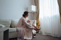 Beautiful bride is preparing for a meeting with her fiance in the white room. Girl in wedding dress in front of the Royalty Free Stock Photo