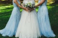 Beautiful bride in puffy dress and veil is holding pastel elegant bouquet in her hands. her bridesmaids in lace light blue dresses