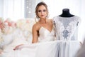 A beautiful bride in a silk night dress shows her wedding dress in the boudoir room.