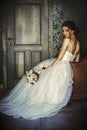 Beautiful bride sits in a leather chair in a dark room