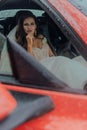 A beautiful bride is sitting in a red car in a white dress and with a bouquet. Wedding Concept Royalty Free Stock Photo