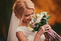 Beautiful bride smelling wedding bouquet in autumn park close up on wedding day Royalty Free Stock Photo