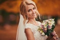 Beautiful bride smelling wedding bouquet in autumn park close up on wedding day Royalty Free Stock Photo