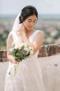 Beautiful bride stand in frind of city view with bouquet and smile Royalty Free Stock Photo