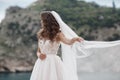 Beautiful bride in white dress posing on sea and mountains in background Royalty Free Stock Photo