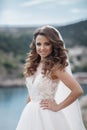 Beautiful bride in white dress posing on sea and mountains in background Royalty Free Stock Photo