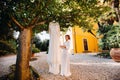 A beautiful bride stands next to a wedding dress with a boudoir attire next to a Villa in Italy.morning of the bride in Tuscany