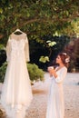 A beautiful bride stands next to a wedding dress with a Cup of tea in a boudoir outfit next to a Villa in Italy.morning of the