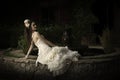 Beautiful bride in strapless vintage wedding dress reclining next to a courtyard fountain Royalty Free Stock Photo