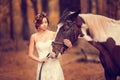 Beautiful bride in a stylish look with a horse on a wedding walk in the autumn park