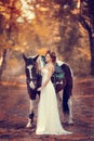 Beautiful bride in a stylish look with a horse on a wedding walk in the autumn park