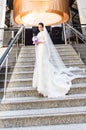 Beautiful bride in stylsh dress stands alone on stairs indoor