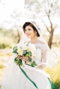 Beautiful bride in tender wedding dress with bridal bouquet in olive grove