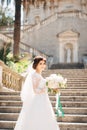 beautiful bride in tender wedding dress with bridal bouquet on the stairs of the Nativity of the Blessed Virgin Mary
