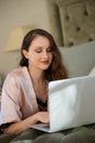 Beautiful bride using laptop while relaxing on bed at home Royalty Free Stock Photo