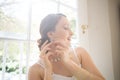 Beautiful bride wearing earring while standing by window Royalty Free Stock Photo