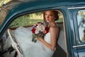 Beautiful bride with wedding bouquet sitting in the car. Royalty Free Stock Photo