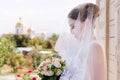 A beautiful bride on a wedding day with a bouquet in hand against the background of an Orthodox Christian church.