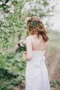 Beautiful bride in a wedding dress with bouquet and roses wreath posing in a green garden Royalty Free Stock Photo