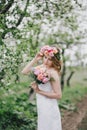 Beautiful bride in a wedding dress with bouquet and roses wreath posing in a green garden Royalty Free Stock Photo