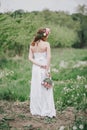 Beautiful bride in a wedding dress with bouquet and roses wreath posing in a green garden Royalty Free Stock Photo