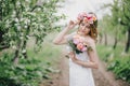 Beautiful bride in a wedding dress with bouquet and roses wreath posing in a green garden Royalty Free Stock Photo