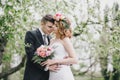Beautiful bride in a wedding dress with bouquet and roses wreath posing with groom wearing wedding suit Royalty Free Stock Photo