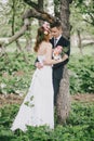 Beautiful bride in a wedding dress with bouquet and roses wreath posing with groom wearing wedding suit Royalty Free Stock Photo