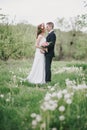 Beautiful bride in a wedding dress with bouquet and roses wreath posing with groom wearing wedding suit Royalty Free Stock Photo