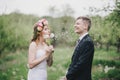 Beautiful bride in a wedding dress with bouquet and roses wreath posing with groom wearing wedding suit