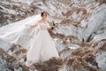 Beautiful bride in a wedding dress with a bouquet on the top of the salt mountains. A stunning young bride with curly hair .