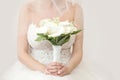 Beautiful bride in a wedding dress holding a bouquet of white zantedeschia. White background.