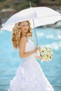 Beautiful bride in wedding dress with white umbrella and bouquet Royalty Free Stock Photo