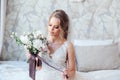 Beautiful bride with wedding flowers bouquet, attractive woman in wedding dress in interier. Royalty Free Stock Photo