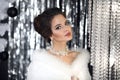 Beautiful bride with wediing set jewelry. Gorgeous brunette girl in white fur coat over Chrismas bokeh background. Bridal winter Royalty Free Stock Photo