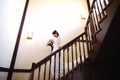 Beautiful bride in a white dress with a bouquet of flowers in her hands goes down the stairs Royalty Free Stock Photo