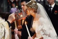 Beautiful bride in white dress kissing crown from a priest at we