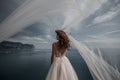 Beautiful bride in white dress posing on sea and mountains in background Royalty Free Stock Photo