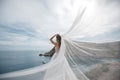 Beautiful bride in white dress posing on sea and mountains in background Royalty Free Stock Photo