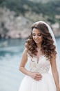 Beautiful bride in white dress posing on sea and mountains in background Royalty Free Stock Photo