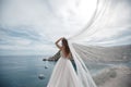 Beautiful bride in white dress posing on sea and mountains in background Royalty Free Stock Photo