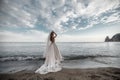 Beautiful bride in white dress posing on sea and mountains in background Royalty Free Stock Photo