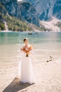 Beautiful bride in a white dress with sleeves and lace, with a yellow autumn bouquet of dried flowers and peony roses