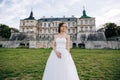 Beautiful bride in white dress stands against the backdrop of an old palace in Europe